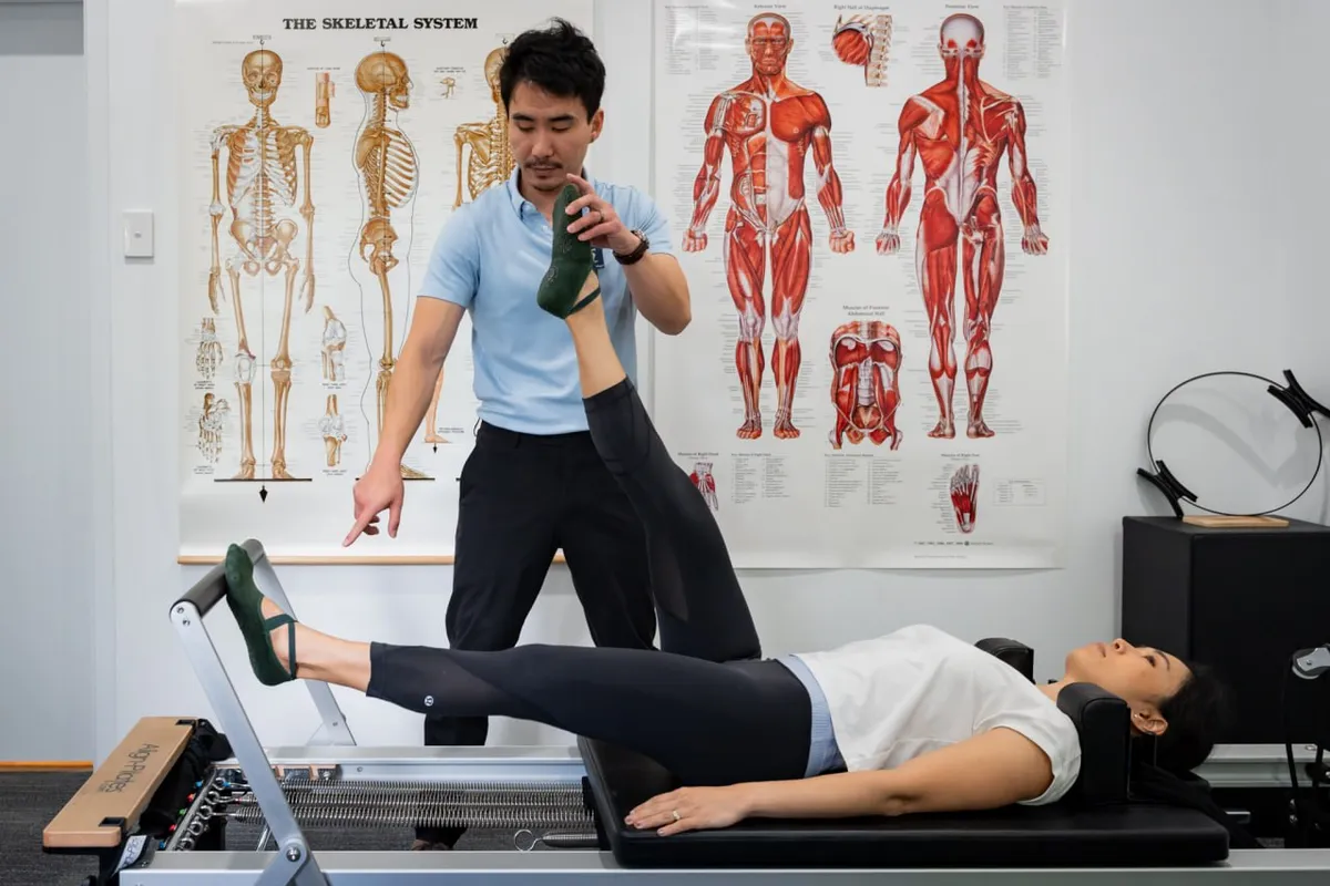 Clyve Tan guiding a client through a stretch in the exercise physiology room