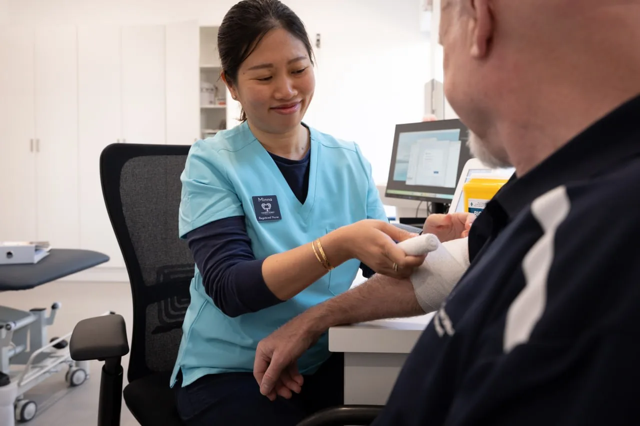 Minna Tran, Registered Nurse at Thorpe Street Health, dressing a patient's hand in the treatment room